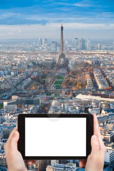 travel concept - tourist photographs Eiffel Tower and panorama of Paris afternoon on tablet pc with cut out screen with blank place for advertising logo