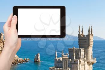 travel concept - tourist photograph Swallow ' s Nest castle and rock Parus (Sail) on Southern Coast of Crimea and Black Sea on tablet pc with cut out screen with blank place for advertising logo