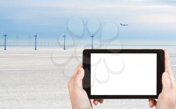 travel concept - tourist photograph Middelgrunden offshore wind farm and oresund bridge near Copenhagen, Denmark on tablet pc with cut out screen with blank place for advertising logo
