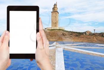 travel concept - tourist photograph ancient roman monument - lighthouse Tower of Hercules, La Coruna, Galicia, Spain on tablet pc with cut out screen with blank place for advertising logo