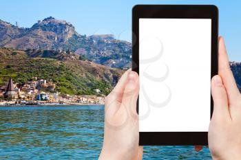 travel concept - tourist photograph Taormina city and Giardini Naxos beach, Sicily, Italy on tablet pc with cut out screen with blank place for advertising logo