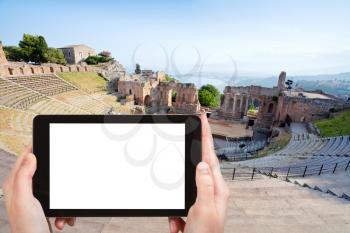travel concept - tourist photograph antique amphitheater Teatro Greco, Taormina, Sicily on smartphone with cut out screen with blank place for advertising logo