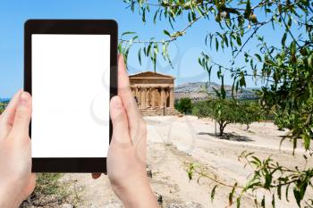 travel concept - tourist photograph Temple on Concordia in Valley of Temples and town Agrigento, Sicily, Italy on tablet pc with cut out screen with blank place for advertising logo