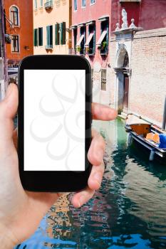 travel concept - tourist photograph canal, boats and bridge in Venice, Italy on smartphone with cut out screen with blank place for advertising logo