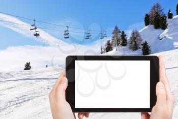 travel concept - tourist photograph ski lift and slope of Dolomites mountains in Val Gardena, Italy on tablet pc with cut out screen with blank place for advertising logo