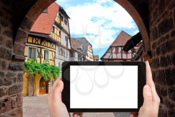 travel concept - tourist photograph central square in Riquewihr town, Alsace, France on tablet pc with cut out screen with blank place for advertising logo
