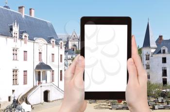 travel concept - tourist photograph courtyard in Castle of the Dukes of Brittany in Nantes, France on tablet pc with cut out screen with blank place for advertising logo