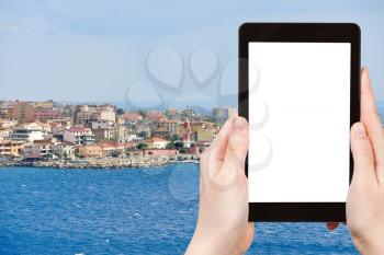 travel concept - tourist photograph Villa San Giovanni of city Reggio di Calabria from Strait of Messina, Italy in summer day on tablet pc with cut out screen with blank place for advertising logo