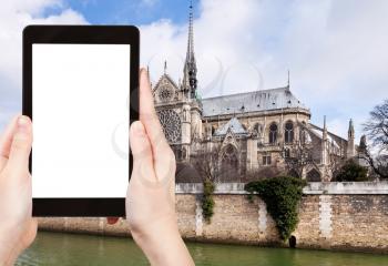 travel concept - tourist photograph cathedral Notre-Dame de Paris and Seine River in cloudy day on tablet pc with cut out screen with blank place for advertising logo