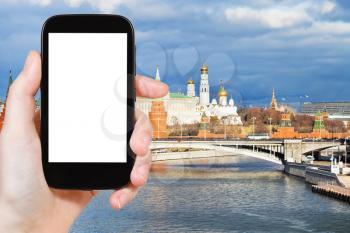 travel concept - tourist photograph Bolshoy Kamenny bridge, Moskva River and Moscow Kremlin in autumn day on smartphone with cut out screen with blank place for advertising logo