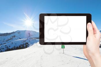 travel concept - tourist photograph skiing tracks on Alps mountains in Portes du Soleil region, Morzine - Avoriaz, France on tablet pc with cut out screen with blank place for advertising logo