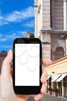 travel concept - tourist photograph Piazza Trento e Trieste with Town Hall and Cathedral in Ferrara, Italy on smartphone with cut out screen with blank place for advertising logo