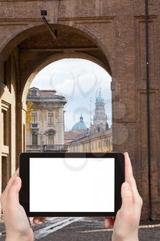 travel concept - tourist photograph cathedral through arch of Palazzo della Pilotta in Parma city, Italy on tablet pc with cut out screen with blank place for advertising logo