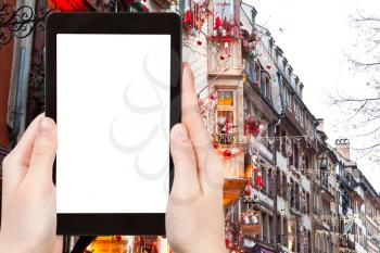 travel concept - tourist photograph urban houses with christmas decoration in Strasbourg, France on tablet pc with cut out screen with blank place for advertising logo