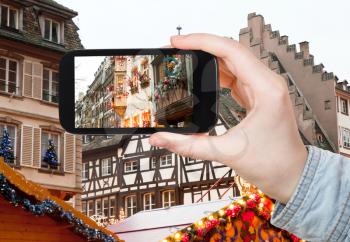 travel concept - tourist takes photo Christmas decoration in Strasbourg urban fair, France on smartphone