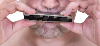 unshaven strolling musician playing harmonica close up