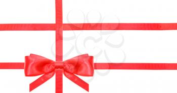 one red satin bow in lower left corner and three intersecting ribbons isolated on horizontal white background