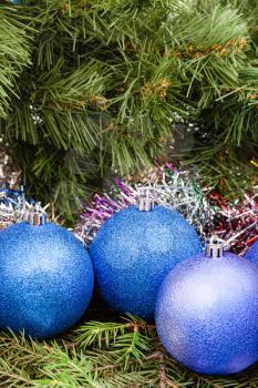 Christmas still life - three blue and violet Christmas balls, tinsel on Xmas tree background