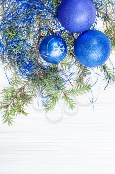 Christmas greeting card - border from three blue and violet Xmas balls and tree branch on blank paper background