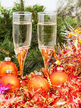 Christmas still life - Two glasses of sparkling wine with golden Xmas decorations on Christmas tree background