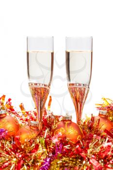 two glasses of champagne at golden and orange Christmas baubles isolated on white background