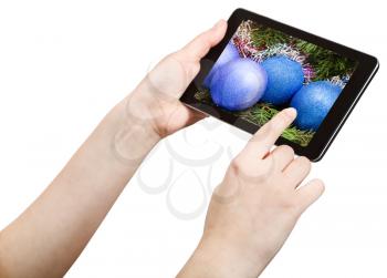 hand touches tablet pc with Christmas decorations on screen isolated on white background