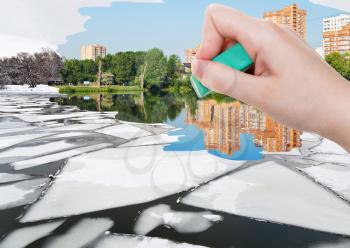 weather concept - hand deletes ice floe near river waterfront in winter by rubber eraser from image and summer cityscape are appearing