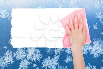 weather concept - hand deletes winter frosty pattern on window by pink rag from image and white empty copy space are appearing