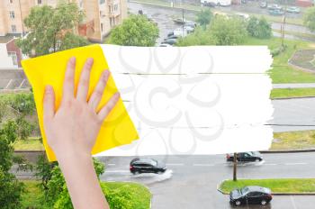 weather concept - hand deletes rain on street by yellow rag from image and white empty copy space are appearing