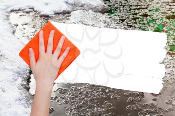 weather concept - hand deletes melting snow by orange rag from image and white empty copy space are appearing
