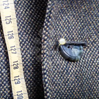 tailor measure tape and half buttoned button on green jacket close up