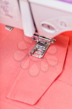 attaching pocket to red shirt on sewing machine close up