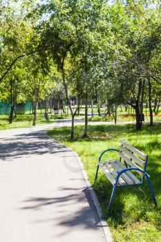 empty bench and walkway in urban public garden in summer day