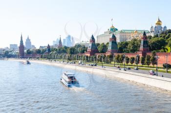 Moscow cityscape - Boats in Moskva River near Kremlin embankment, Kremlin buildings, walls, towers in summer afternoon
