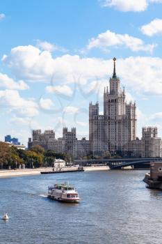 Moscow cityscape - boat in Moskva river and view of Moskvoretskaya Embankment, Bolshoy Ustinsky Bridge and Kotelnicheskaya Embankment High-Rise Building in Moscow, Russia in summer day