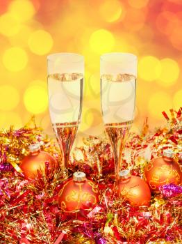 Christmas still life - two glasses of champagne at golden Xmas decorations with yellow and red blurred Christmas lights bokeh background