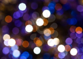 abstract blurred background - dark blue and violet shimmering Christmas lights bokeh of electric garlands on Xmas tree