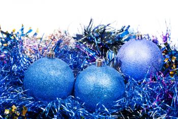 three blue Christmas balls and tinsel isolated on white background