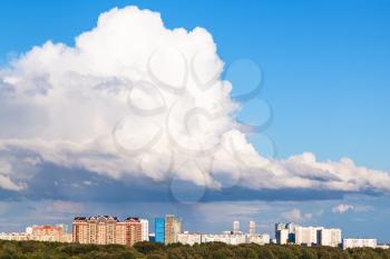 large low white cloud in blue sky over city in summer day