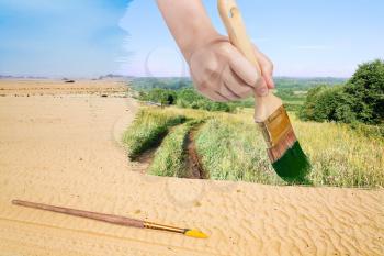 nature concept - seasons and weather changing: hand with paintbrush paints green countryside in sand desert