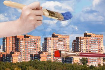 nature concept - hand with paintbrush paints blue clouds over modern urban buildings