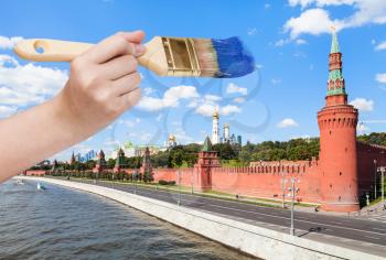 travel concept - hand with paintbrush paints blue sky over Moscow Kremlin