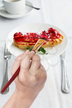 food concept - hand paints by paintbrush of red glaze on eclair