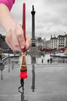travel concept - hand paints by paintbrush the red umbrella of people walking on Trafalgar square in London in rainy day