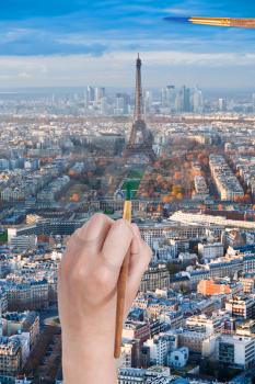 travel concept - hand with paintbrush paints in green colour Champ de Mars near Eiffel tower in Paris city, France