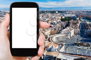 travel concept - hand holds smartphone with cut out screen and St. Peter's Square in Vatican on background