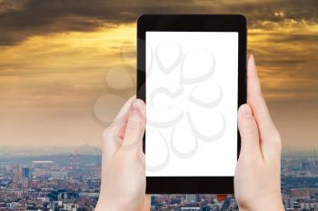 travel concept - hand holds tablet pc with cut out screen and smog over city on background