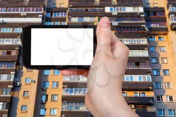 travel concept - hand holds smartphone with cut out screen and facade on appartment house in Moscow on background