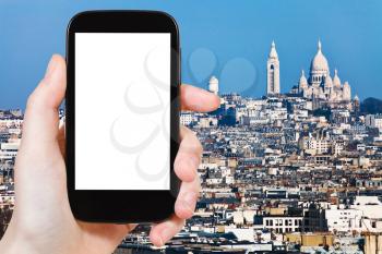 travel concept - hand holds smartphone with cut out screen and Montmartre Hill in Paris on background