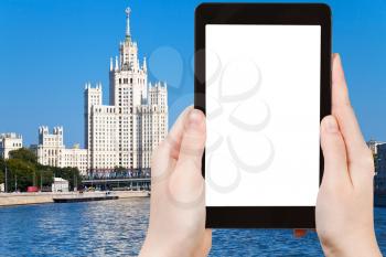 travel concept - hand holds tablet pc with cut out screen and Moscow skyscraper on background
